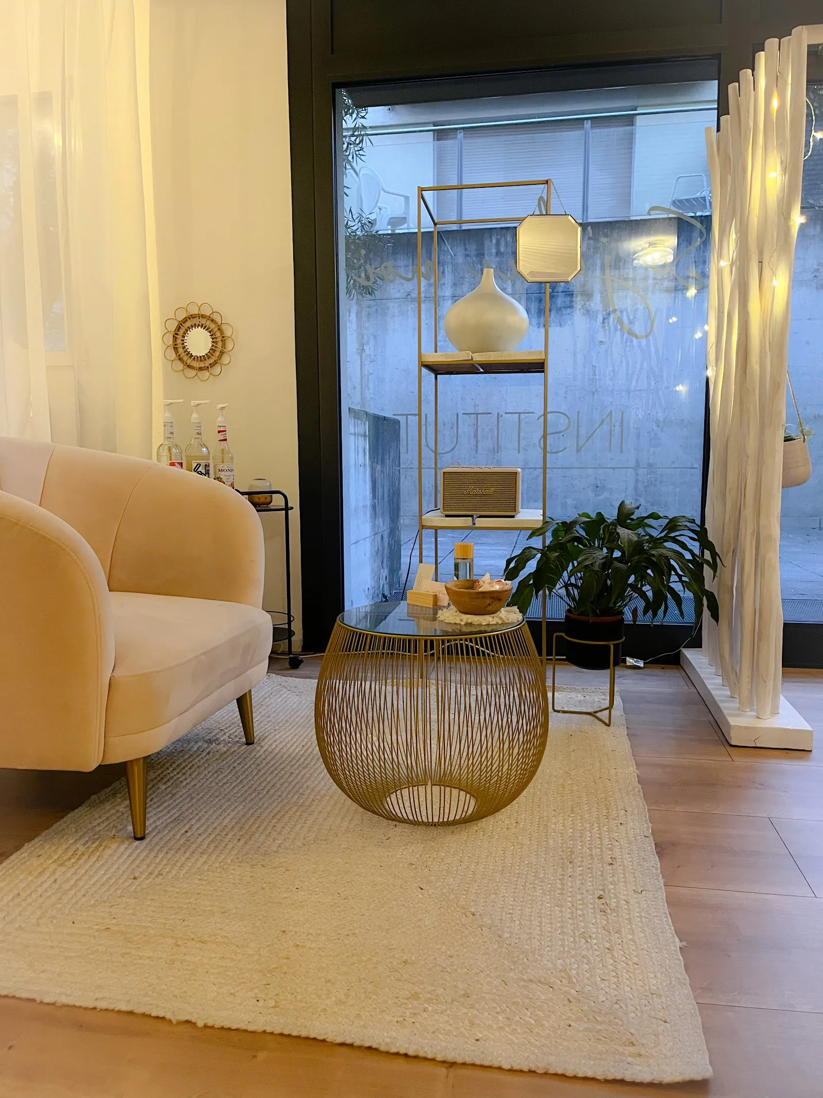 Le salon d'accueil de l'institut : fauteuil en velours rose poudré, table dorée et paravent en bois clair